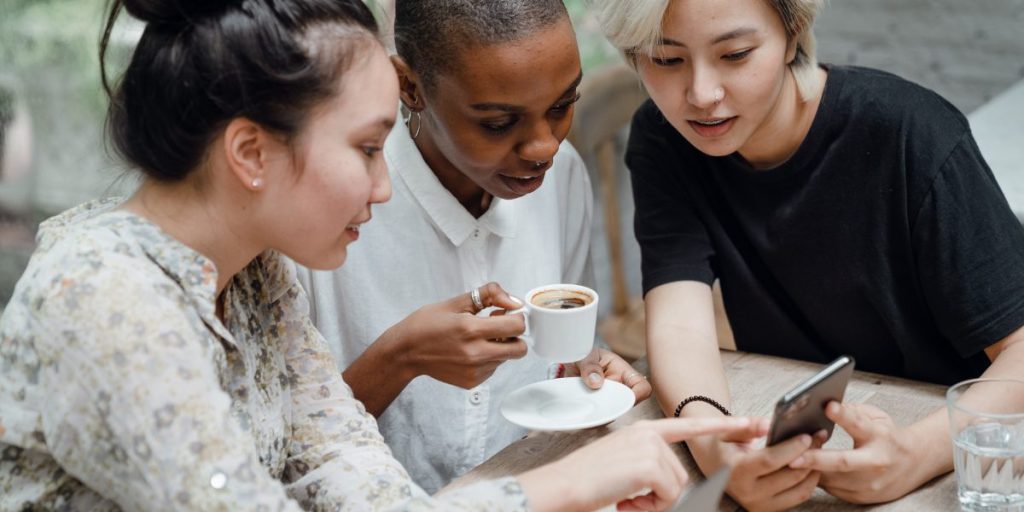three women watching something on a mobile phone